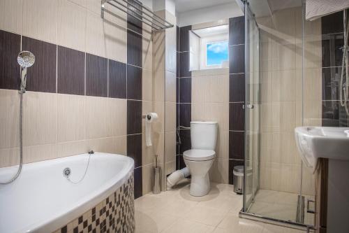 y baño con bañera, aseo y lavamanos. en Garden apartments, en Prešov