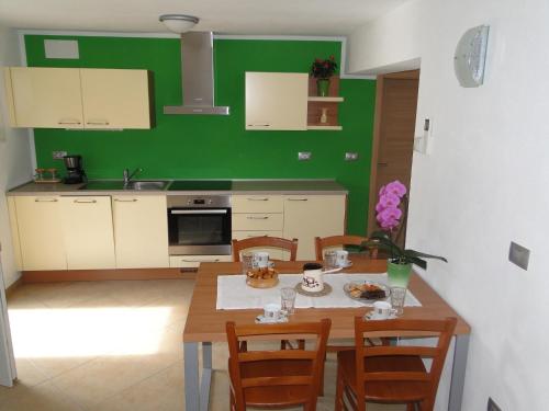eine Küche mit einem Tisch und Stühlen sowie einer grünen Wand in der Unterkunft Apartma Jezero in Most na Soči