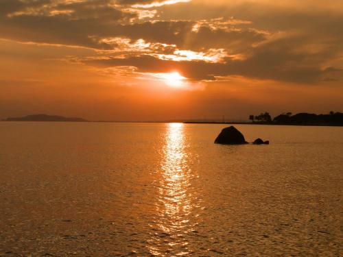 a sunset over the water with a rock in the middle at Gangdigiorgia in Capitana
