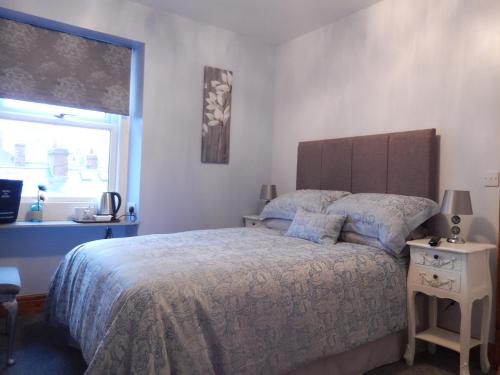 a bedroom with a large bed and a window at Shore to Shore in Llandudno