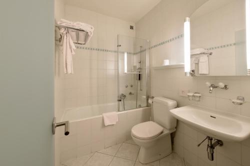 a white bathroom with a toilet and a sink at Hôtel Bellerive in Lausanne