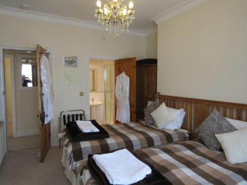a bedroom with two beds and a chandelier at Harringtons at 14 in Llandudno