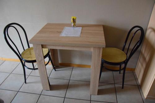 a wooden table with two chairs and a drink on it at Condo Gardens Antwerp in Antwerp