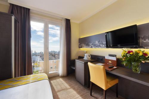 a hotel room with a desk and a tv at Hôtel Bellerive in Lausanne
