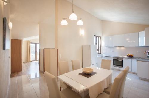 una cucina e una sala da pranzo con tavolo e sedie bianchi di Apartments Kate a Makarska