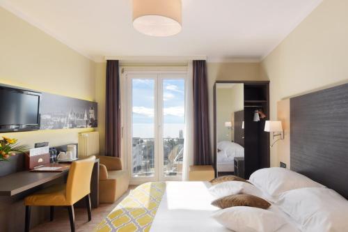 a hotel room with a bed and a desk and a window at Hôtel Bellerive in Lausanne