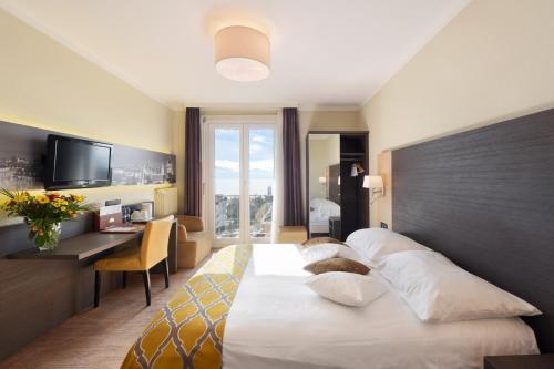 a hotel room with a large bed and a desk at Hôtel Bellerive in Lausanne