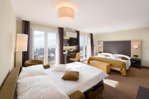 a hotel room with two beds and a large window at Hôtel Bellerive in Lausanne