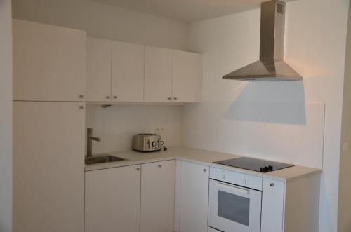 eine Küche mit weißen Schränken, einer Spüle und einem Toaster in der Unterkunft Apartment Beach in Blankenberge