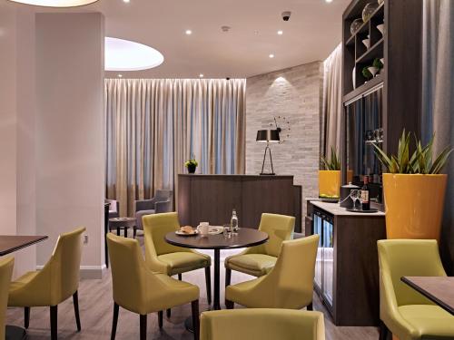 a restaurant with a table and yellow chairs at Best Western Plus Vauxhall Hotel in London
