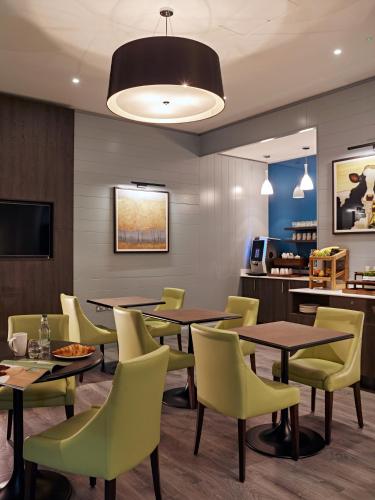 a dining room with tables and yellow chairs at Best Western Plus Vauxhall Hotel in London