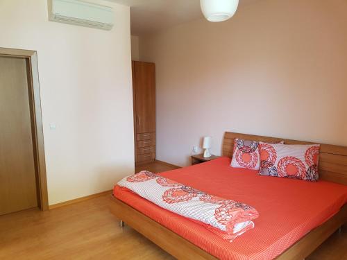a bedroom with a bed with red sheets and pillows at Villa Ketli Apartment in Bliznatsi