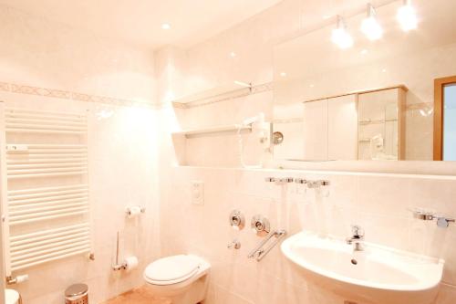ein weißes Badezimmer mit Waschbecken und Toilette in der Unterkunft Schlösschen am Schmachter See by Rujana in Binz
