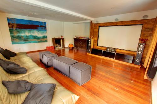 a living room with two couches and a large screen at Pousada Vila Boa Vida in Bombinhas