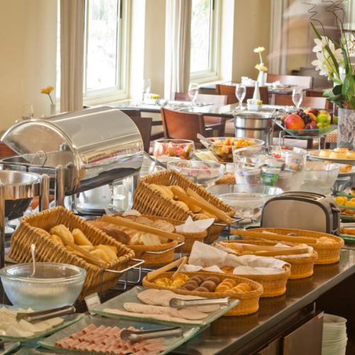a buffet line with baskets of bread and other food at Bourbon Residence Barra da Tijuca - Rio de Janeiro in Rio de Janeiro