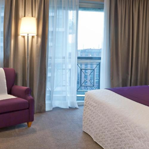 a bedroom with a bed and a chair and a window at Bourbon Residence Barra da Tijuca - Rio de Janeiro in Rio de Janeiro