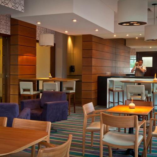 a lobby with tables and chairs and a person talking on a cell phone at Bourbon Residence Barra da Tijuca - Rio de Janeiro in Rio de Janeiro