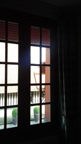 a window view of a building with potted plants at Aux Trois Damoiselles in Beuvron-en-Auge