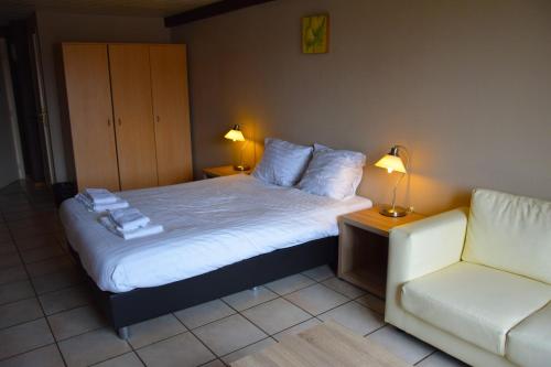 a bedroom with a bed and a white couch at Condo Gardens Antwerp in Antwerp