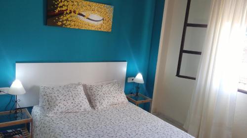 um quarto com uma cama branca e uma parede azul em Apartamento Zulema em Aracena