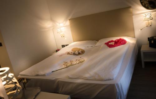a bed with white sheets and red roses on it at Fantinello Hotel in Caorle