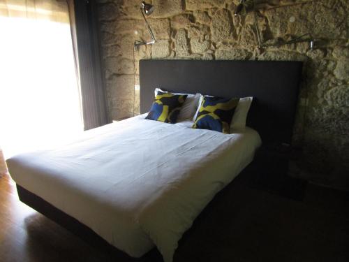 a large bed in a bedroom with a stone wall at Quinta do Medronheiro Hotel Rural in Viseu