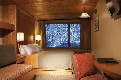 a bedroom with a bed and a large window at Sunshine Mountain Lodge in Banff