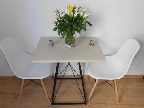 a white table with a vase of flowers and two chairs at Dan In'n Out in Vienna