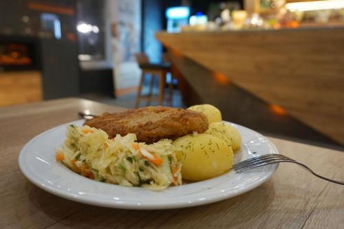a plate of food with meat and coleslaw on a table at Villa Winterpol in Karpacz
