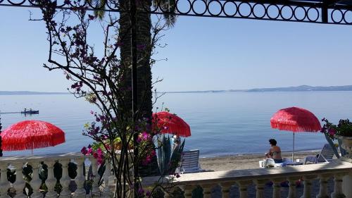 a person sitting on a beach with red umbrellas at Hotel Lido - Beach and Palace in Bolsena