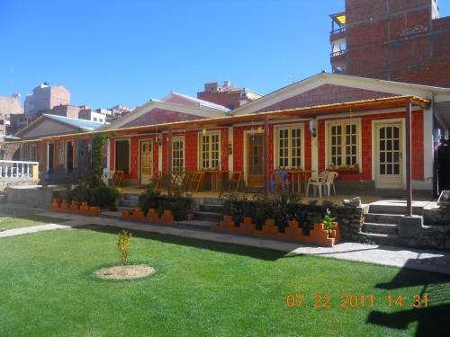a red house with a lawn in front of it at Hostal La Casa del Sol in Copacabana