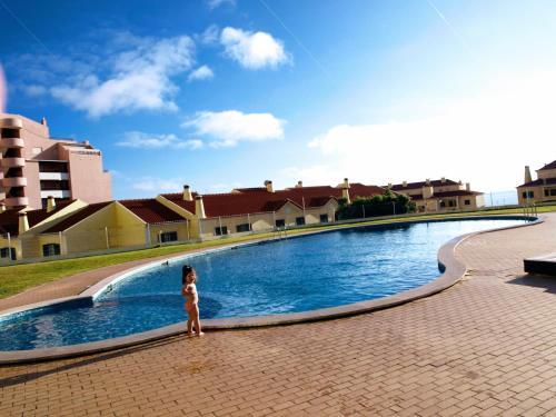 a little girl standing in front of a swimming pool at Apartment Ericeira in Ericeira