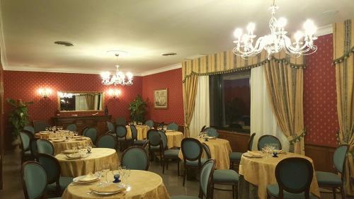 a dining room with tables and chairs and a chandelier at Hotel Royal in Bolsena