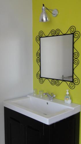 a bathroom sink with a mirror on a yellow wall at B&B De Gastfabriek in Tielt