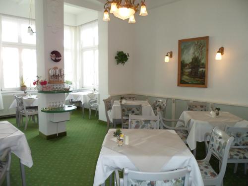 ein Restaurant mit weißen Tischen, Stühlen und Fenstern in der Unterkunft Hotel Schloonsee Garni in Bansin