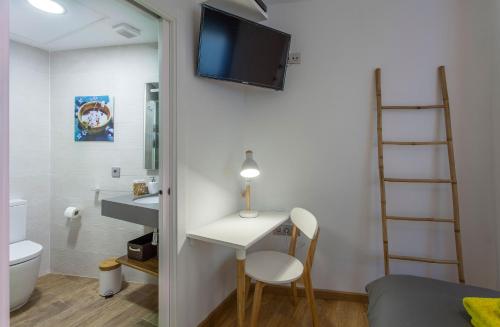 een kleine kamer met een bureau en een tv aan de muur bij City Garden Bed and Breakfast in Valencia