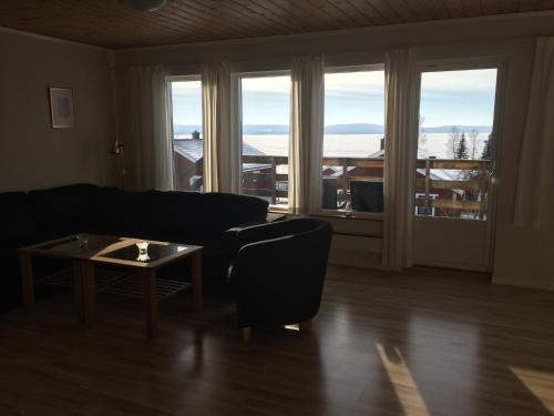 a living room with a couch and a table and windows at Siljan Utsikt Semesterhus in Sjurberg