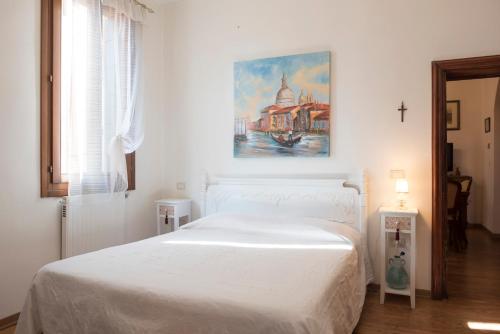 a bedroom with a white bed with a painting on the wall at La Galea in Venice