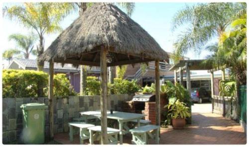 a patio area with a table, chairs, and umbrellas at Anchorage Motor Inn in Caloundra