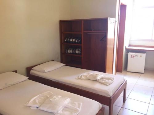 two twin beds in a room with a cabinet at Hospedagem Chamonville in Belo Horizonte