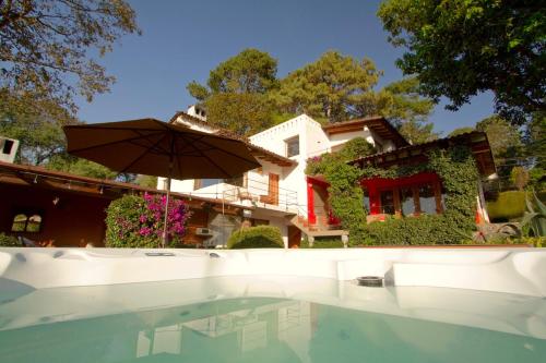 a house with a swimming pool and an umbrella at Las Luciernagas (Adults Only) in Valle de Bravo