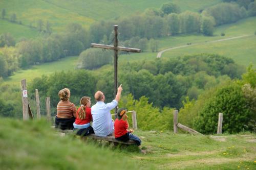 a man sitting on a bench with three children around a cross at Landhaushotel Hof Wasserkuppe in Poppenhausen