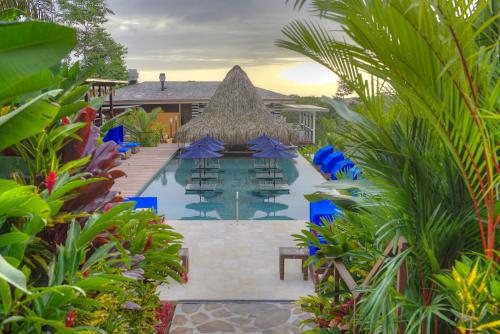 a pool with chairs and umbrellas in a resort at Nayara Springs - Adults Only in Fortuna