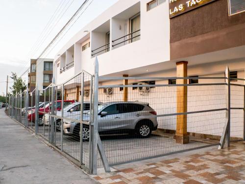 two cars parked in a parking lot in front of a building at Hotel & Spa Las Taguas in Arica