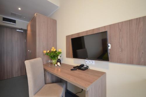 a room with a desk with a television on a wall at Hotel Zorza in Kołobrzeg
