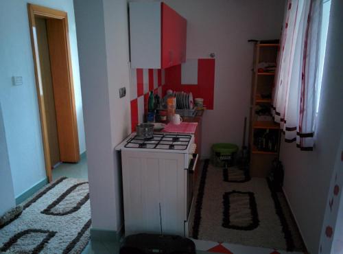 eine kleine Küche mit einem Herd und roten Schränken in der Unterkunft Holiday Home Dvoslap in Bihać