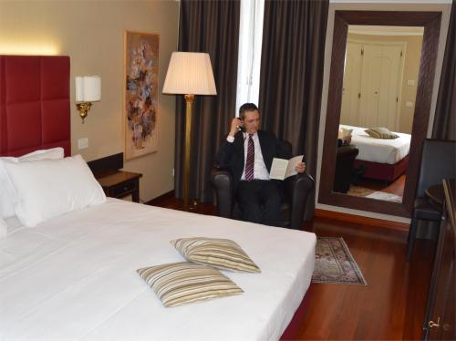 a man talking on a cell phone in a hotel room at Astoria Hotel Italia in Udine