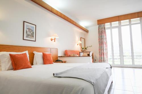 um quarto com uma cama grande e uma janela grande em Hotel Pantanha Nature & Fitness nas Caldas da Felgueira