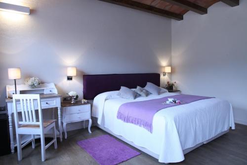 a bedroom with a white bed and a desk and a chair at Hotel Rural Can Vila in Sant Esteve de Palautordera