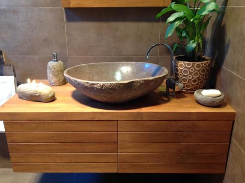 a bathroom with a bowl sink on a wooden counter at Mistinthegumtrees Eco Luxury Cabins in Cooranbong